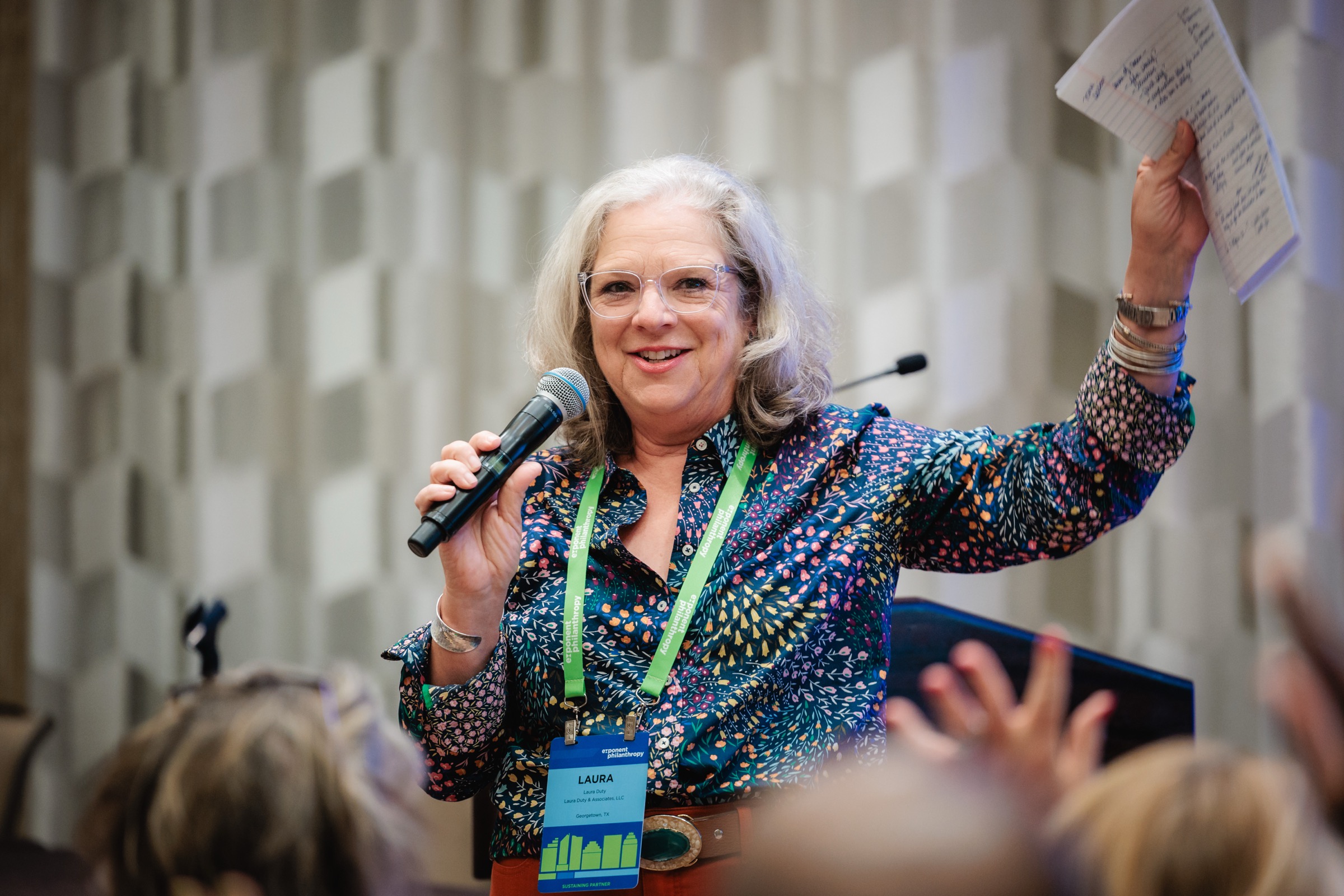 Laura mid-session, microphone in one hand and notes raised in the other