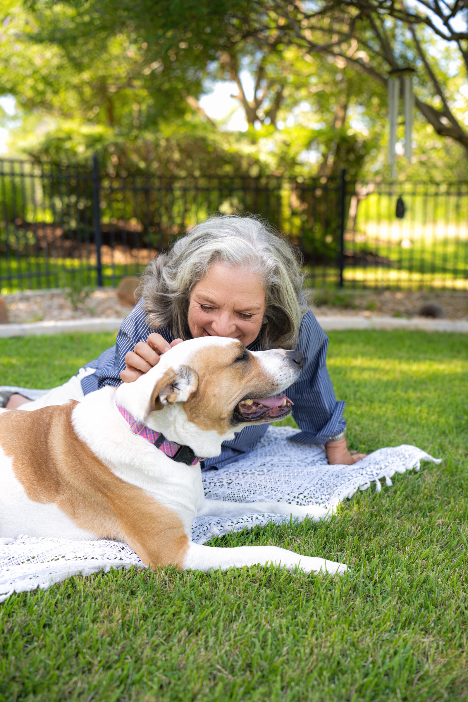 Laura lying on a blanket in the yard, laughing with her dog