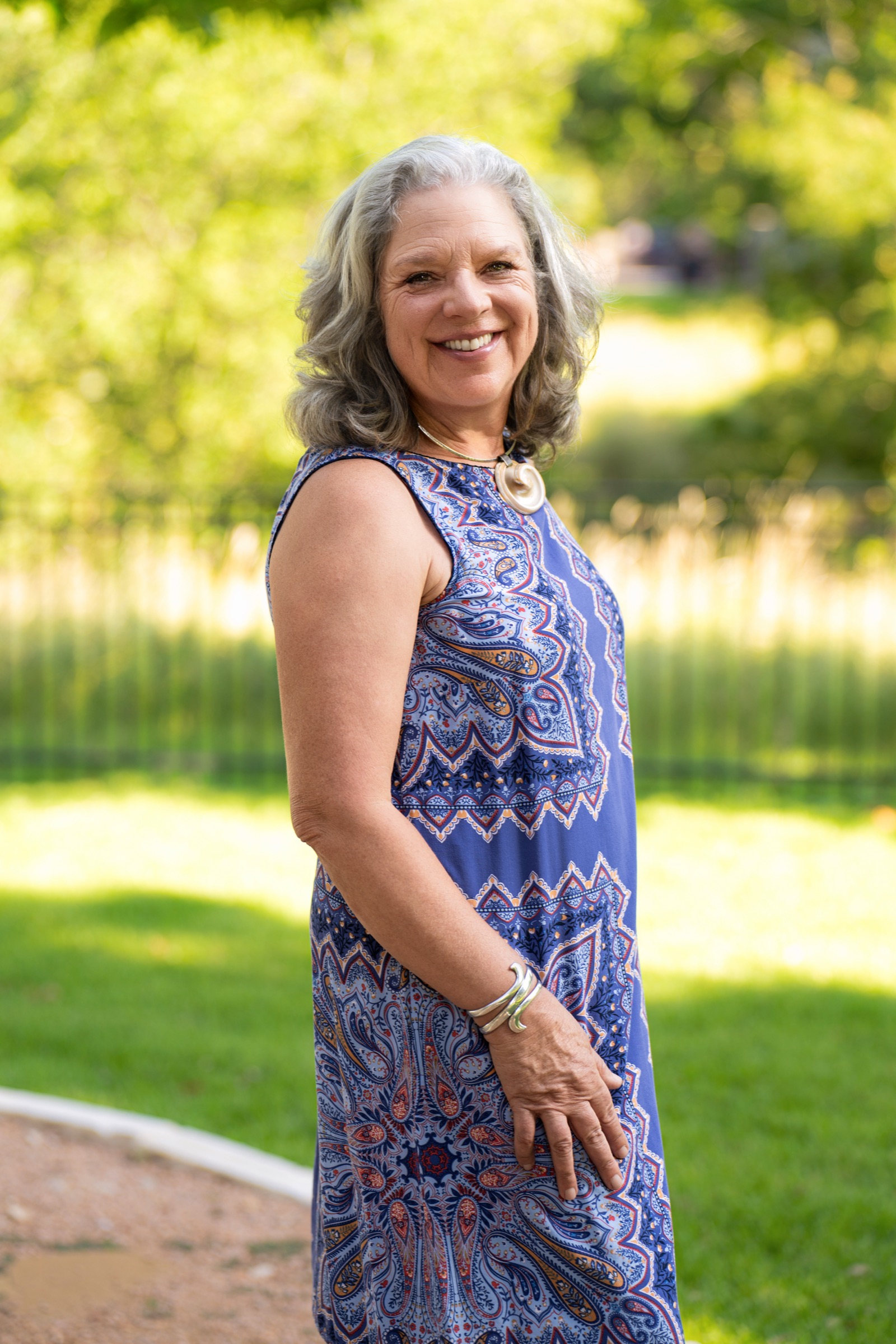Laura outdoors in a paisley dress, turned toward the camera and smiling