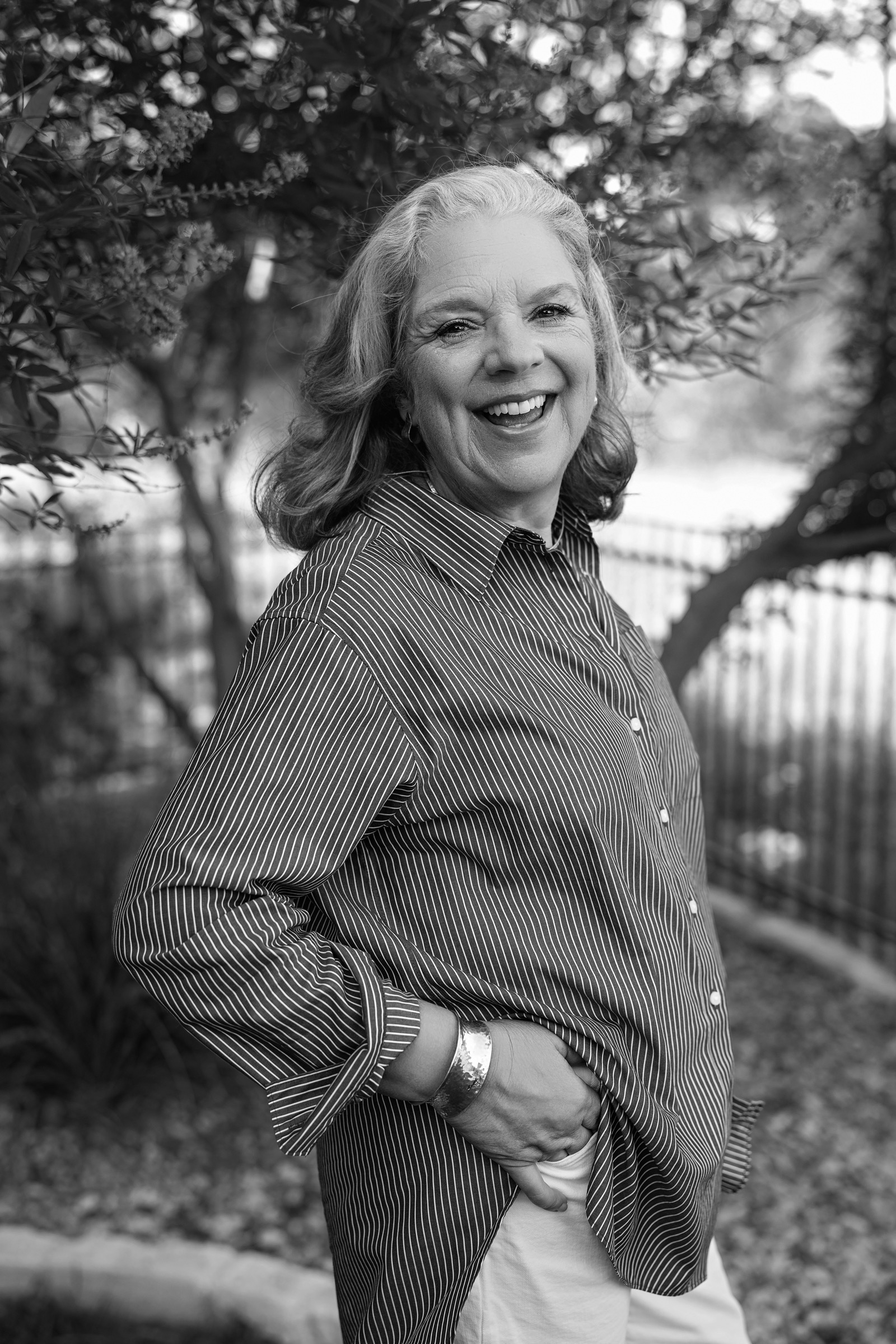A quieter portrait of Laura in black and white, standing under crepe myrtle branches