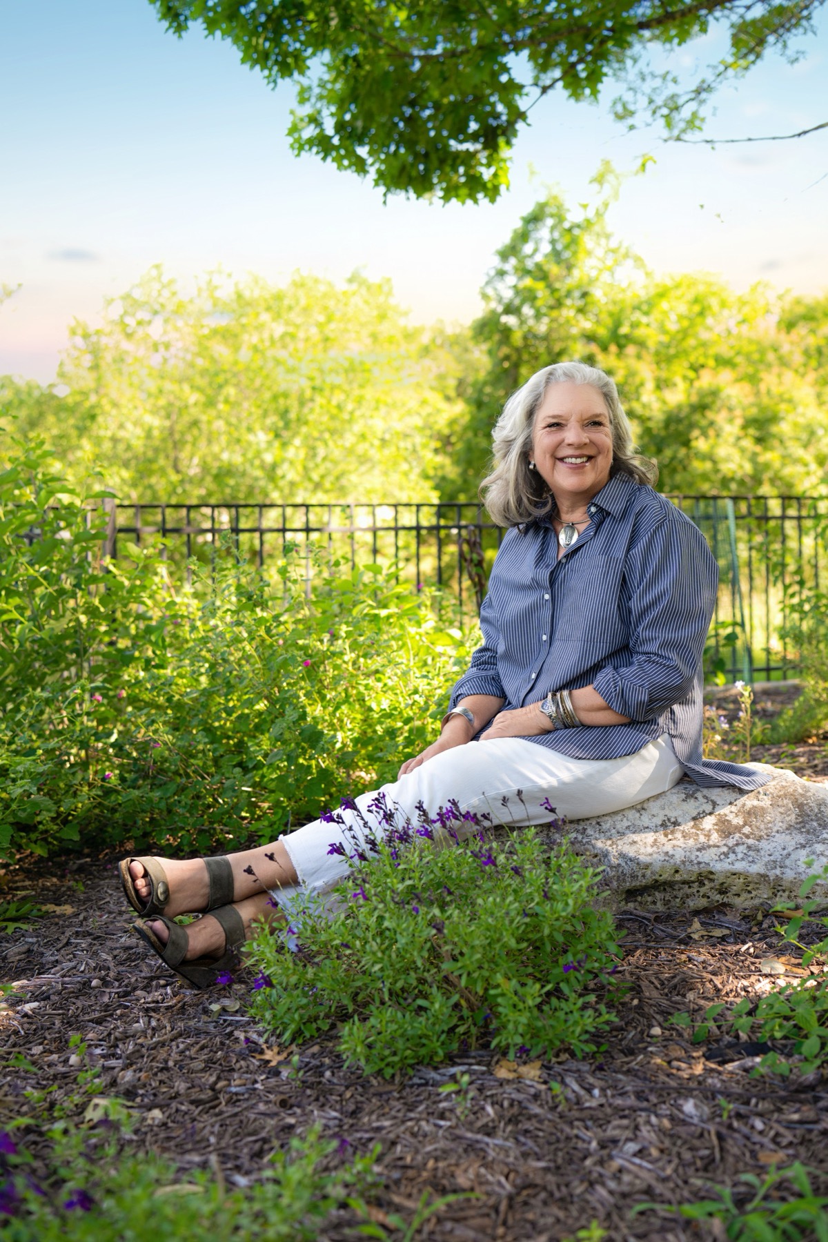 Laura seated on a limestone boulder in her garden at golden hour