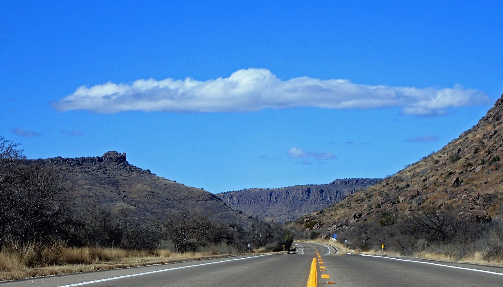 A two-lane highway bending away between desert hills
